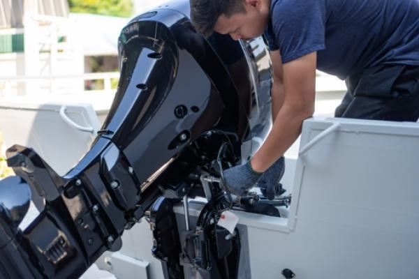 Mechanic working on outboard motor at Wawautosa Marina